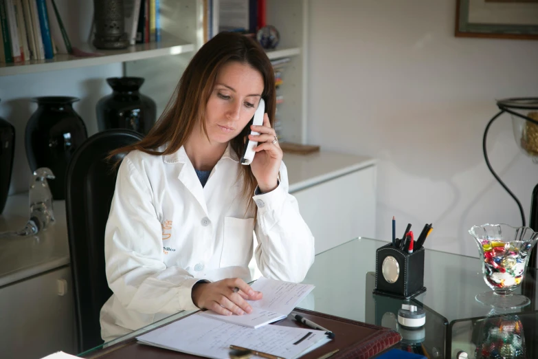 a woman in a white lab coat sitting at a desk