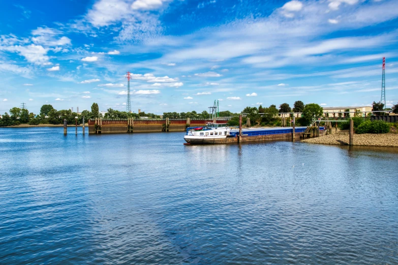 a blue sky with clouds, blue and white ship and a blue building