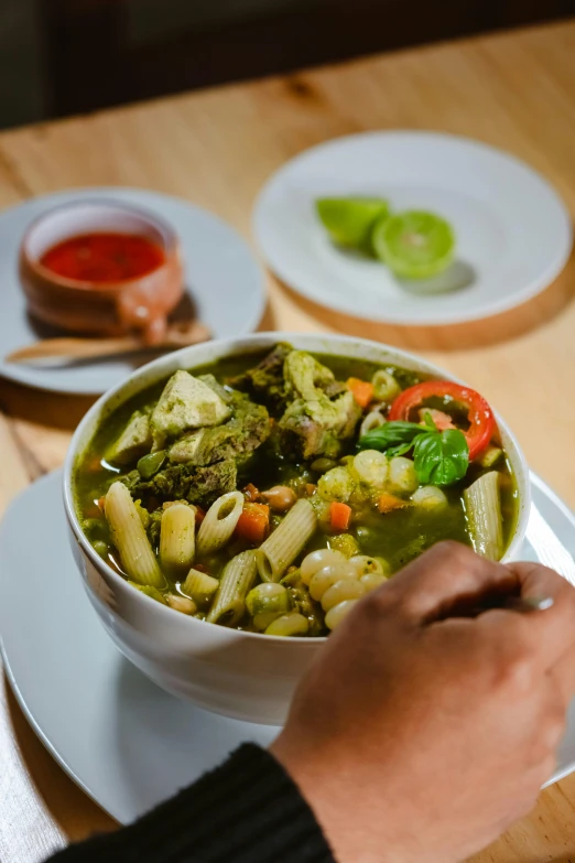 a bowl with noodles in green sauce and vegetables