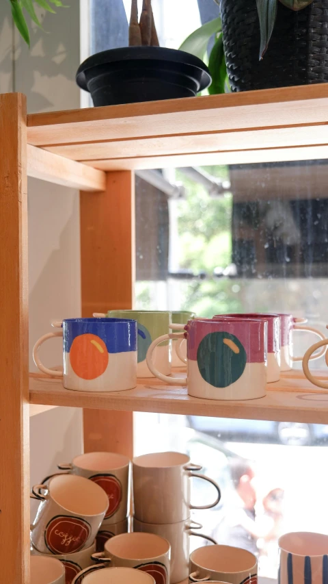 coffee cups are sitting on a shelf by the window