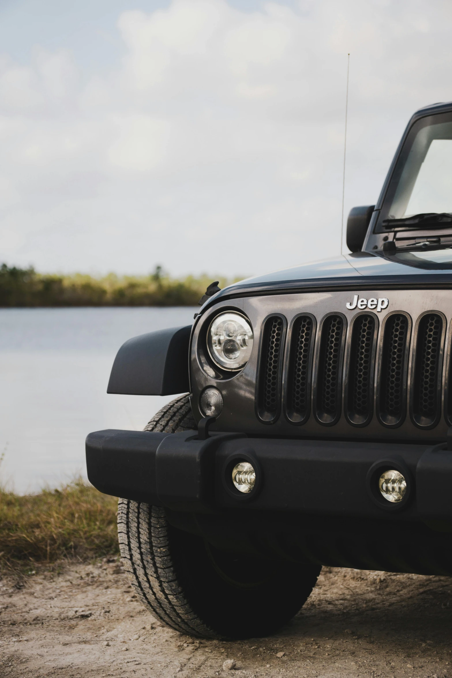 the front of a jeep parked near a lake