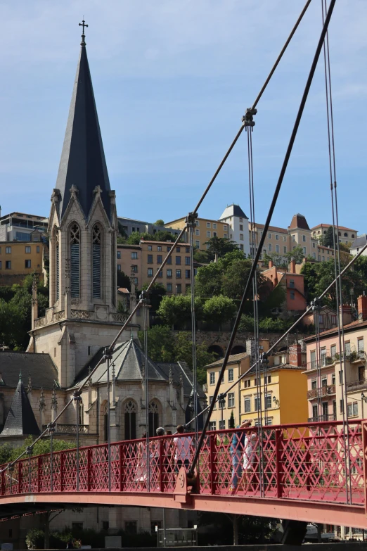 a red bridge with some pink buildings and a very old church