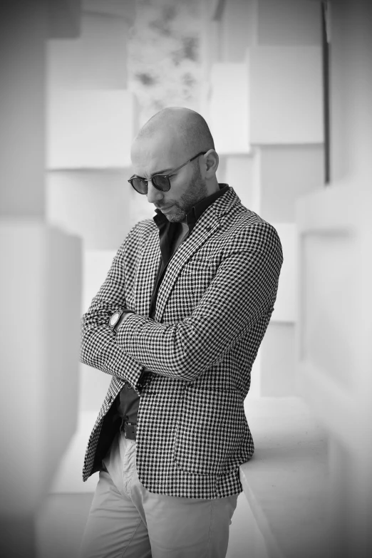 a bald man in a jacket standing and posing