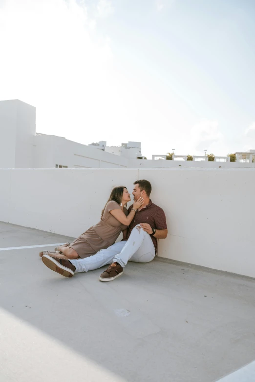 two people sitting down on the ground, sharing a kiss