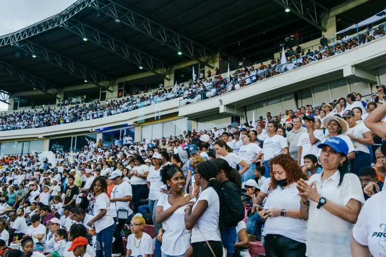 many people are standing in the crowd at a tennis match