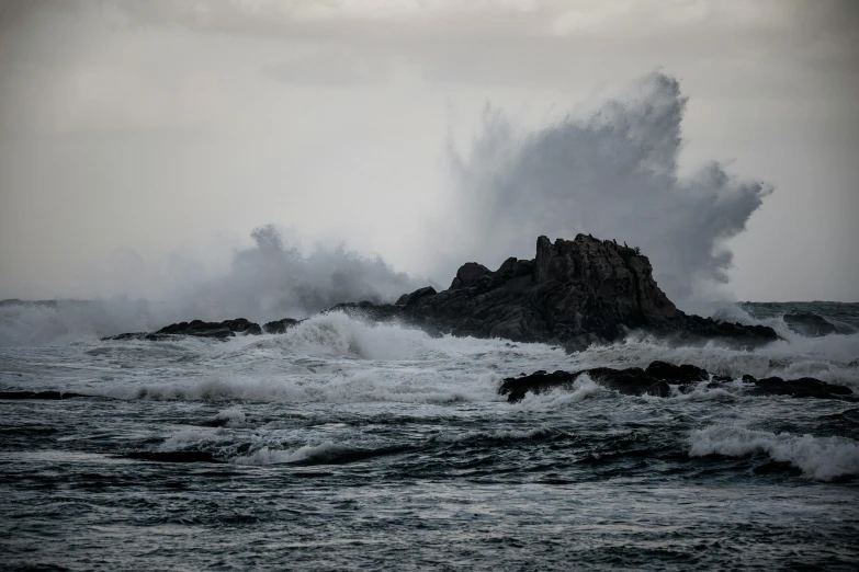 an ocean crashing with a rock in the background