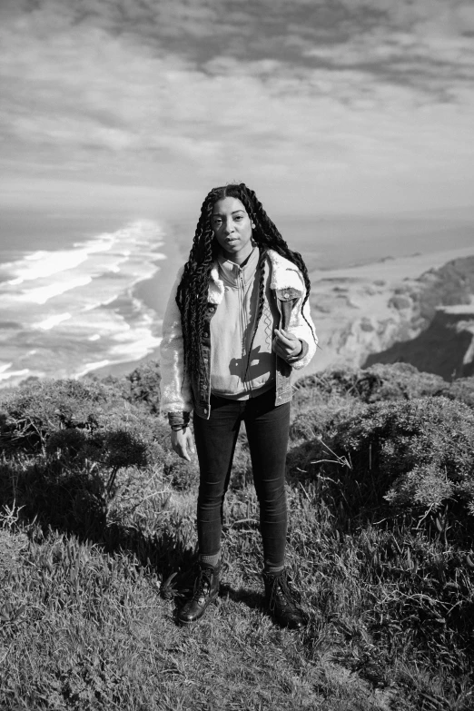 a woman with long hair is standing on the top of a hill