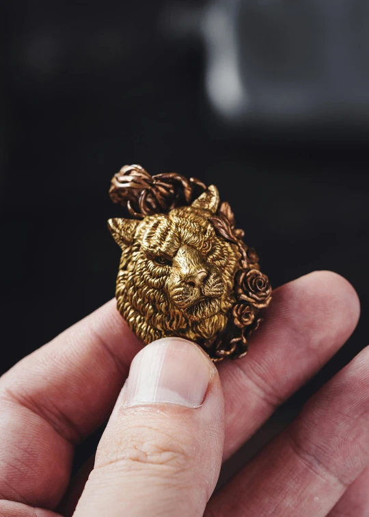 a hand holding an ornate gold brooch