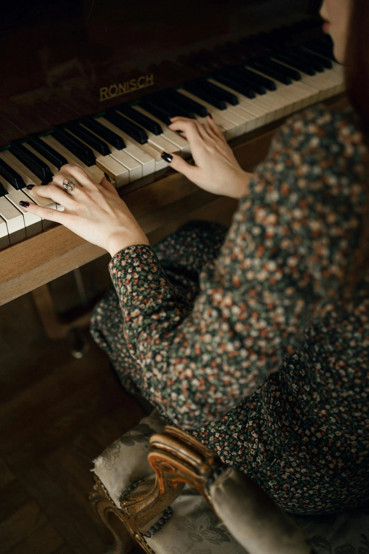 hands playing a musical piano in a small room