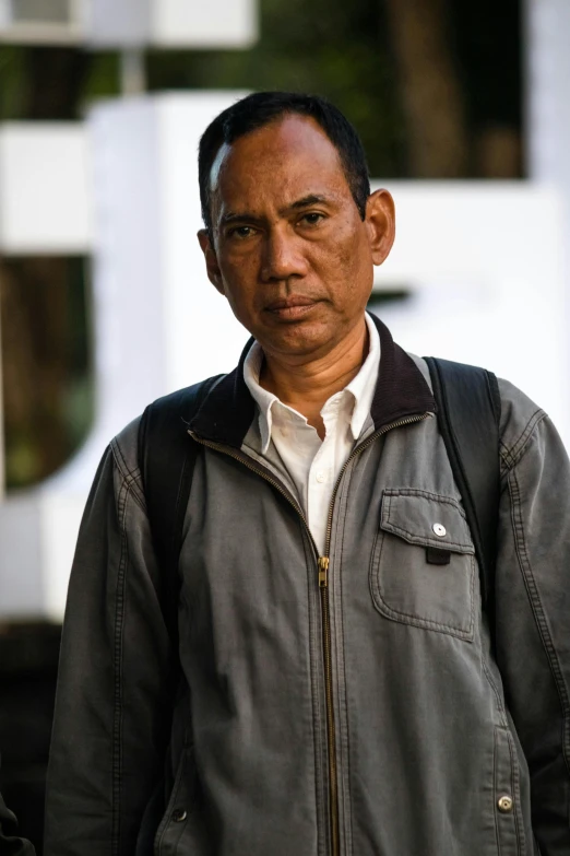 a man wearing a jacket and white shirt is walking