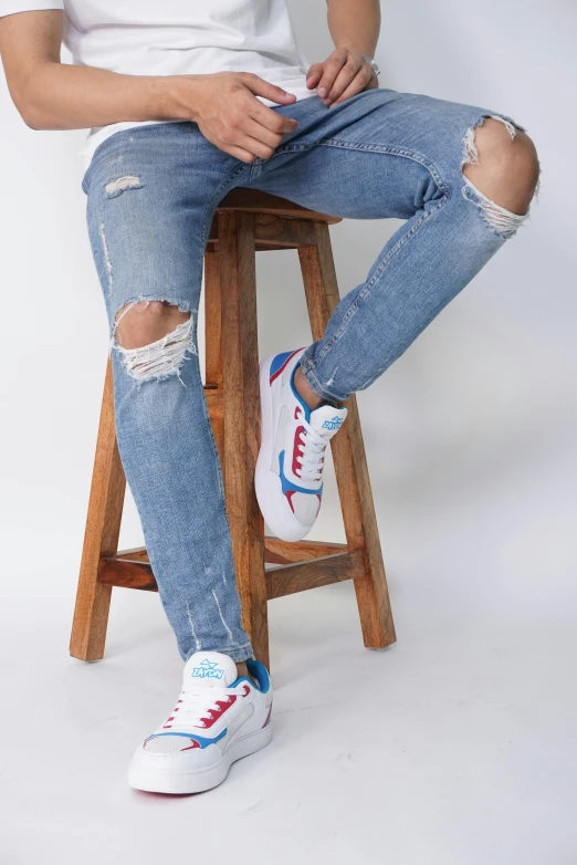 a person is sitting on a stool with ripped jeans