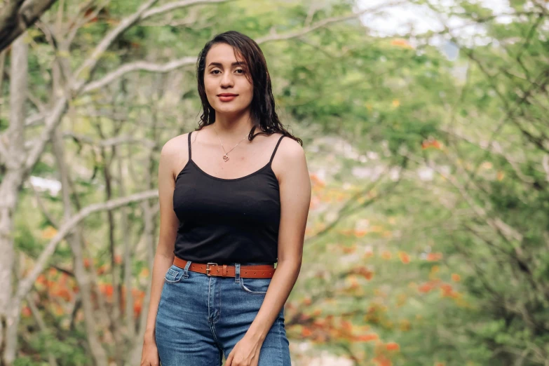 a woman standing next to trees in the woods