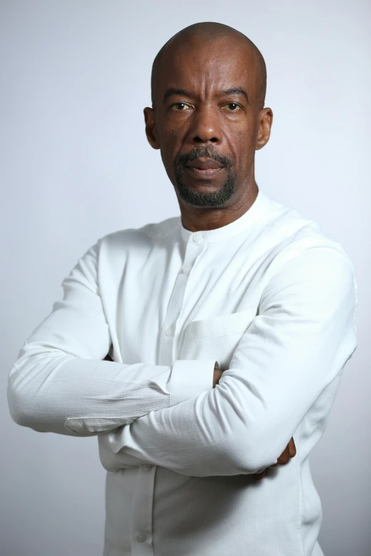 an african american man in white clothes poses for a portrait