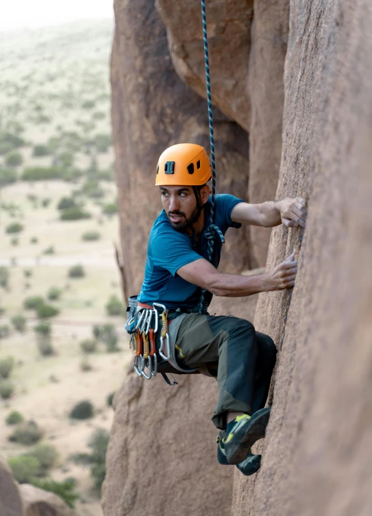 the man is rock climbing while wearing safety equipment