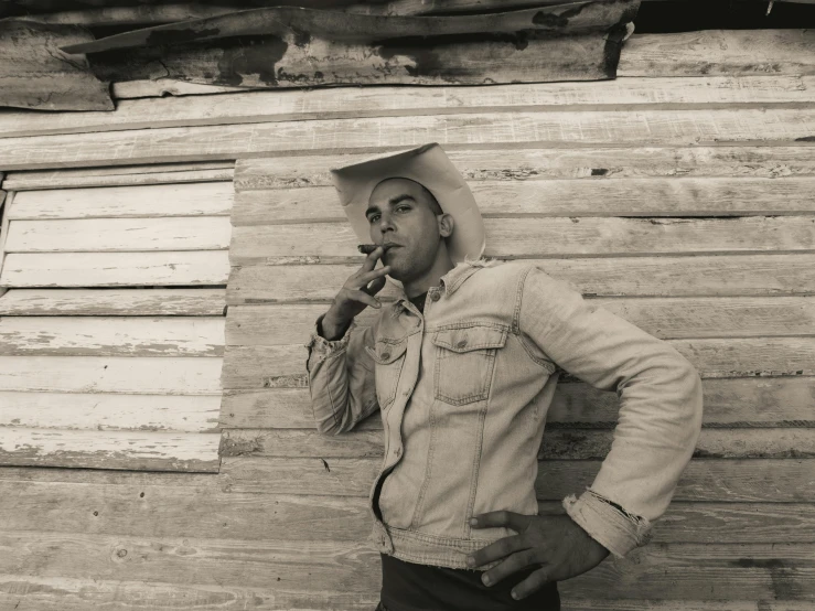 a man standing against a building smoking a cigarette