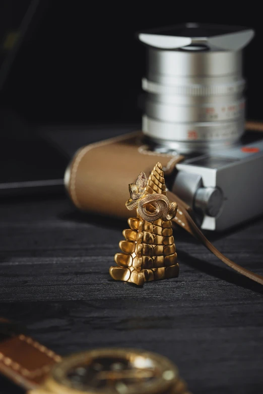 a gold object on a table with an old camera nearby