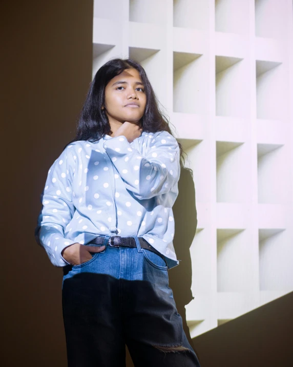 a little girl wearing a blue polka dot shirt and jean pants