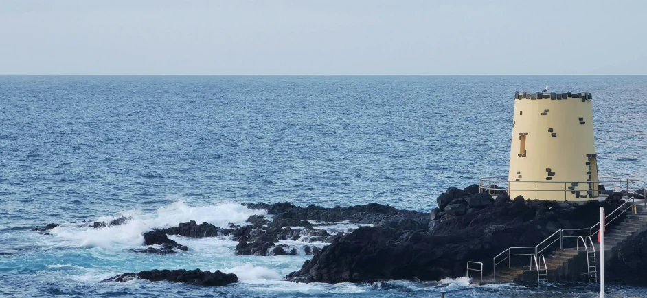 a light house near some water and rocky cliffs