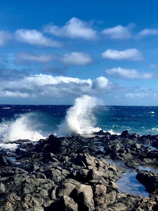 a wave is hitting the rocks along a beach