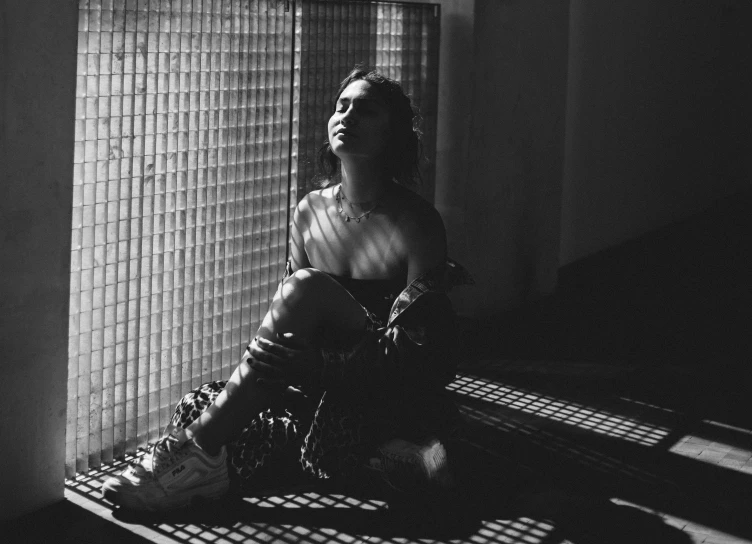 a woman in a tank top is sitting on a window sill