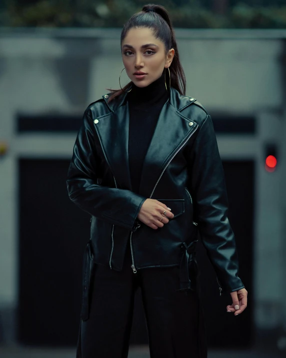 a woman wearing a black leather jacket standing in the street