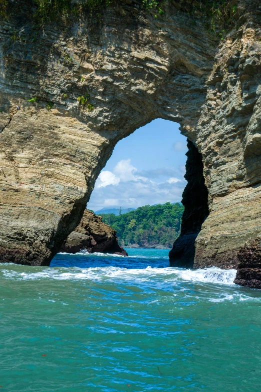 an open - sided stone arch in the sea with a water surface below