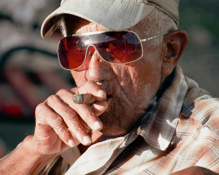 an old man wearing sunglasses and smoking a cigar