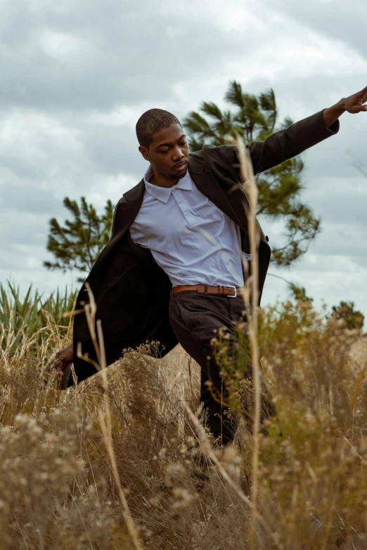 a man walking through the tall grass holding his arms out