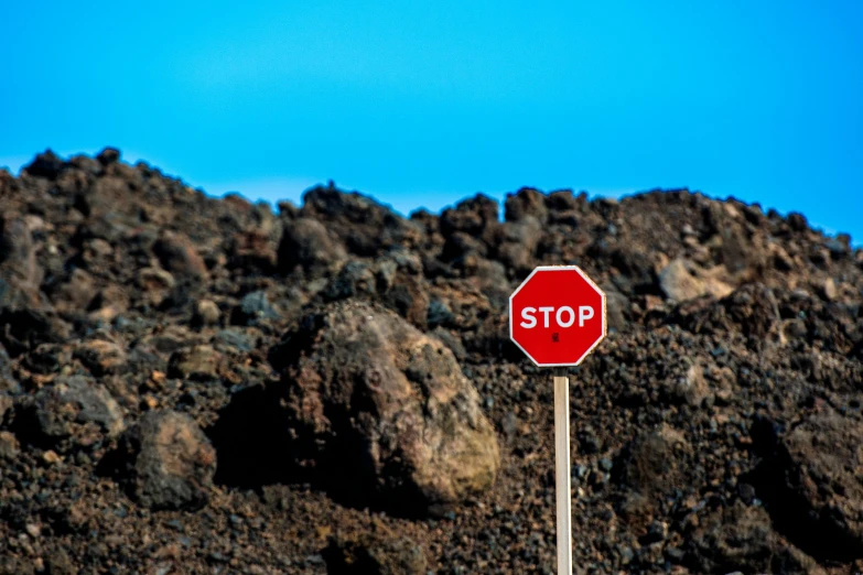 a stop sign on the side of a rocky mountain