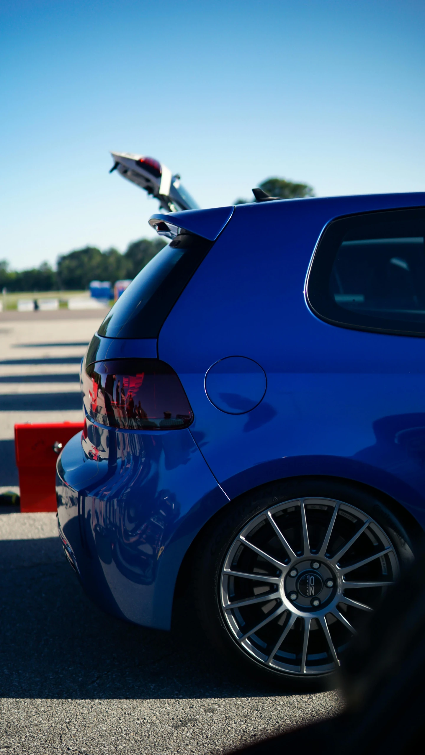 a blue car sits on the pavement with its door open