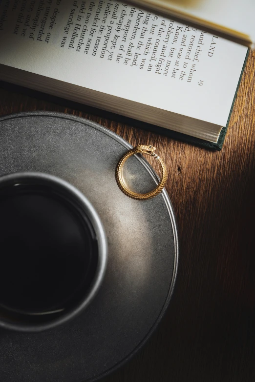 two rings on a plate and a coffee cup with a book in the background