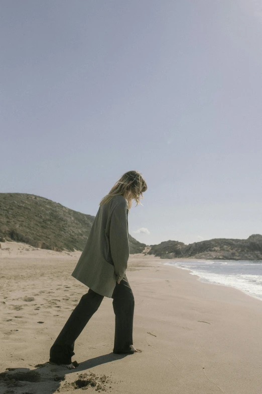 a woman walking on the beach near the water