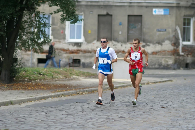 two men race in a marathon past the camera