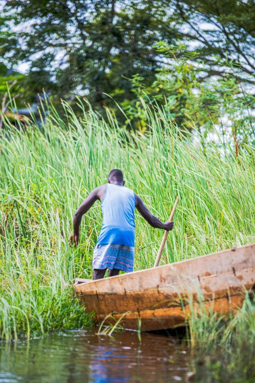 a man holding the edge of a long wooden canoe