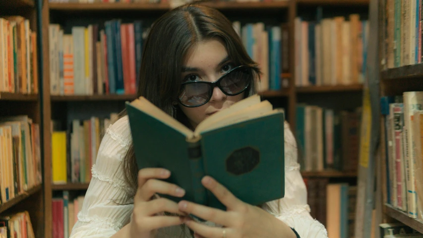 a girl with dark glasses on her head reading a book