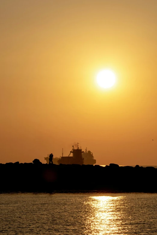 the sunset over the water and silhouette of a boat