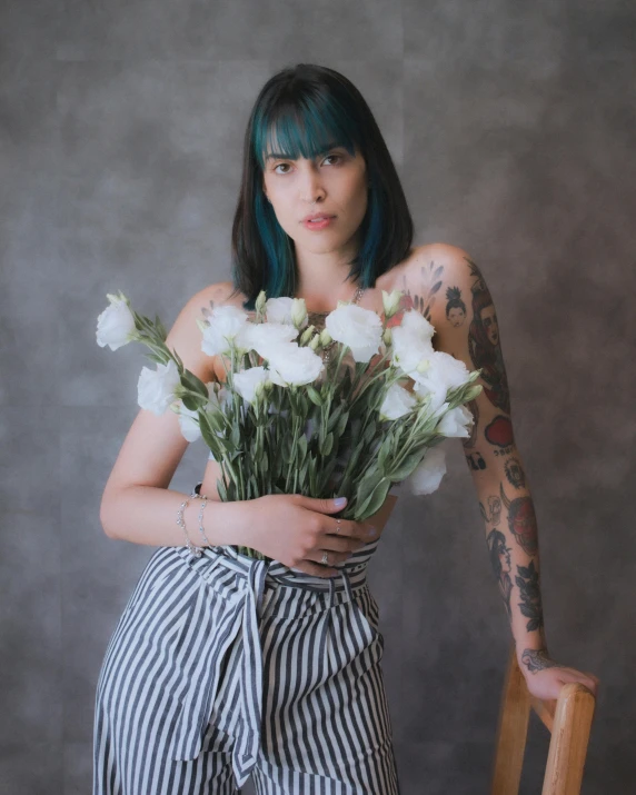 a girl with tattoos holding onto a bouquet of flowers