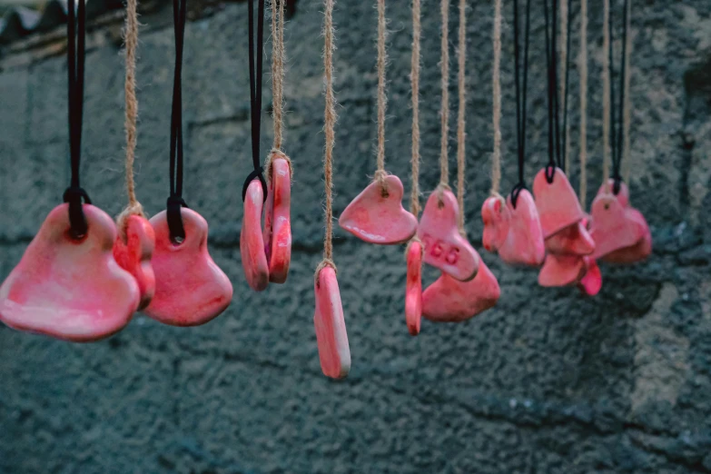 pink pieces of plastic hanging next to a gray wall