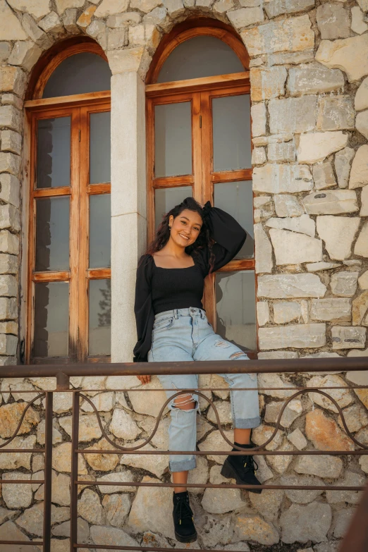 a woman is posing in a window on the side of a stone building