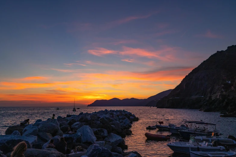 the sunset shines brightly on the rocky shore of the bay