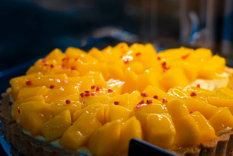 a dessert is decorated with mango slices and red flakes