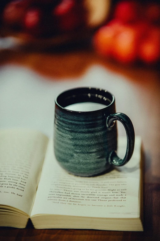 the book is open to reveal a small black mug on top of a table