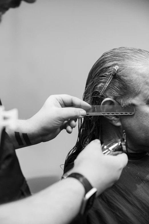 a woman getting her hair styled while another person combs her hair