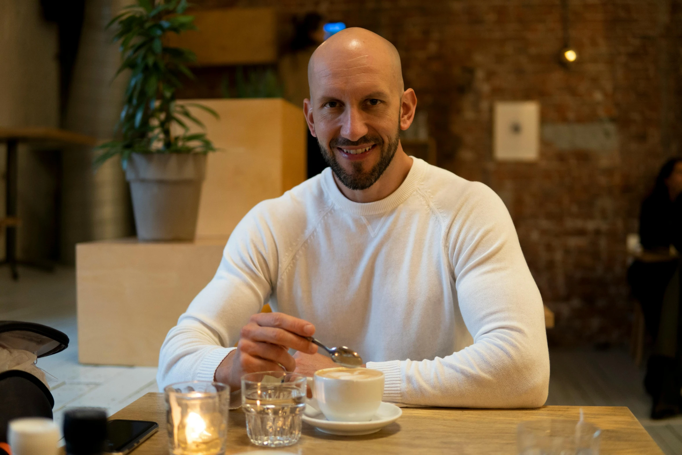 a man sitting at a table with drinks and a pastry