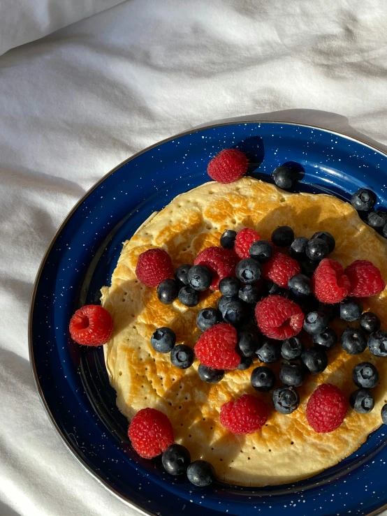 pancakes and berries are on a plate with white tablecloth