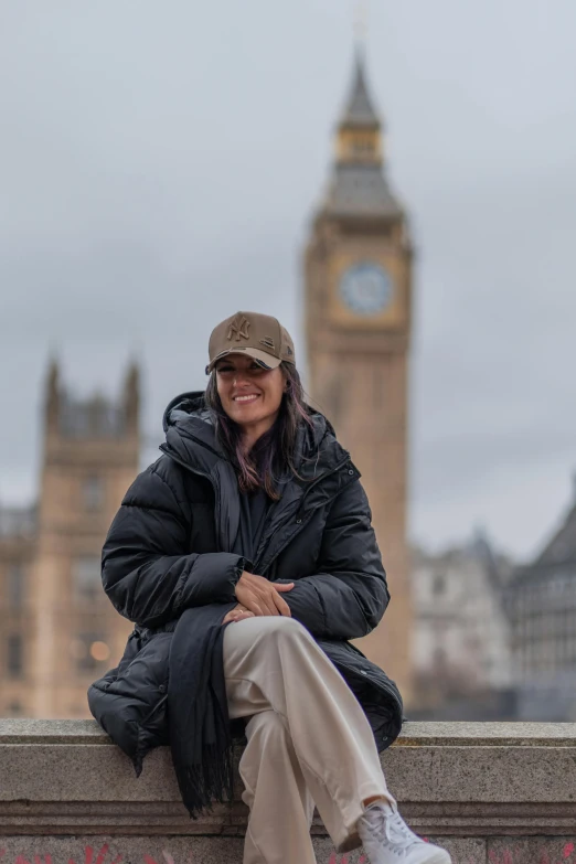 the woman is sitting on the ledge beside the building