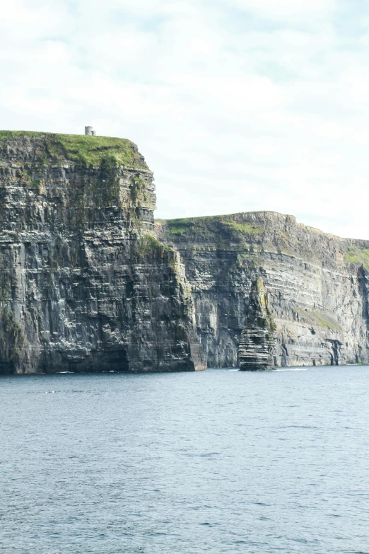 the boat is floating in the open water near cliffs