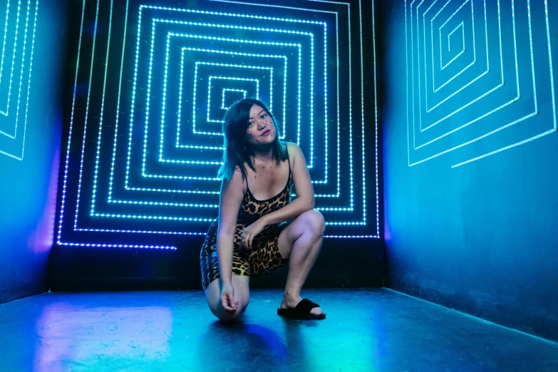 a woman in black dress posing on the ground with an illusion background