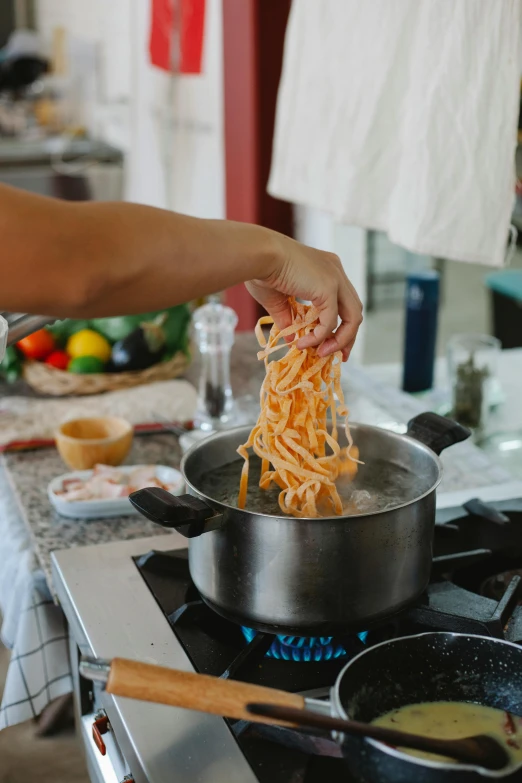 a person is stirring noodles in a pan