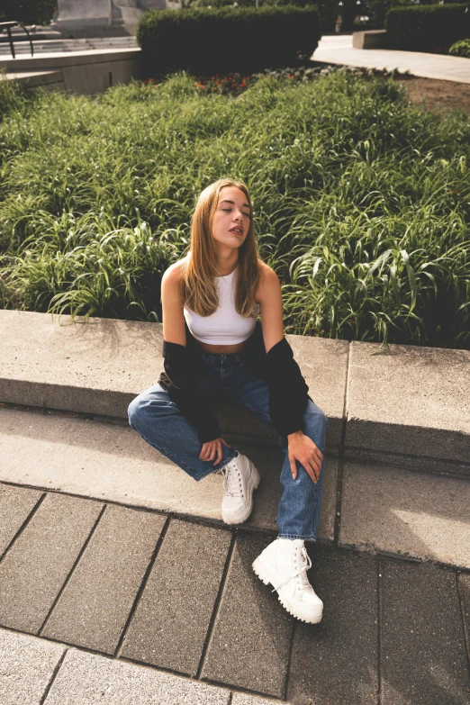 a woman sits on the curb with flowers in front